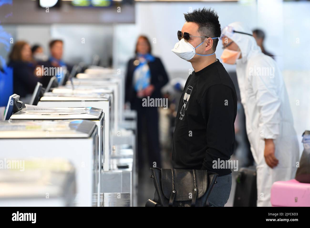 People in personal protective equipment are seen at the baggage checkin