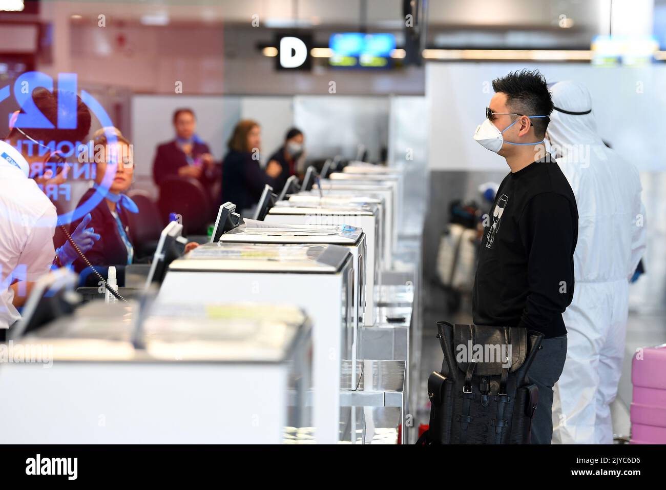 People in personal protective equipment are seen at the baggage checkin