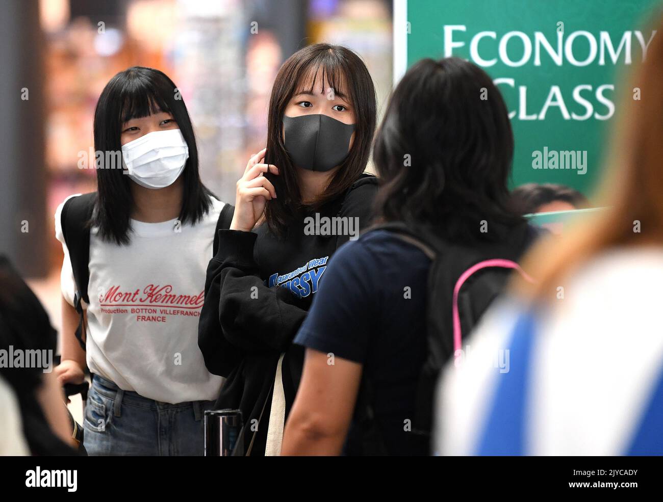 Passengers wear face masks as they wait to check in at Brisbane International Airport, Wednesday
