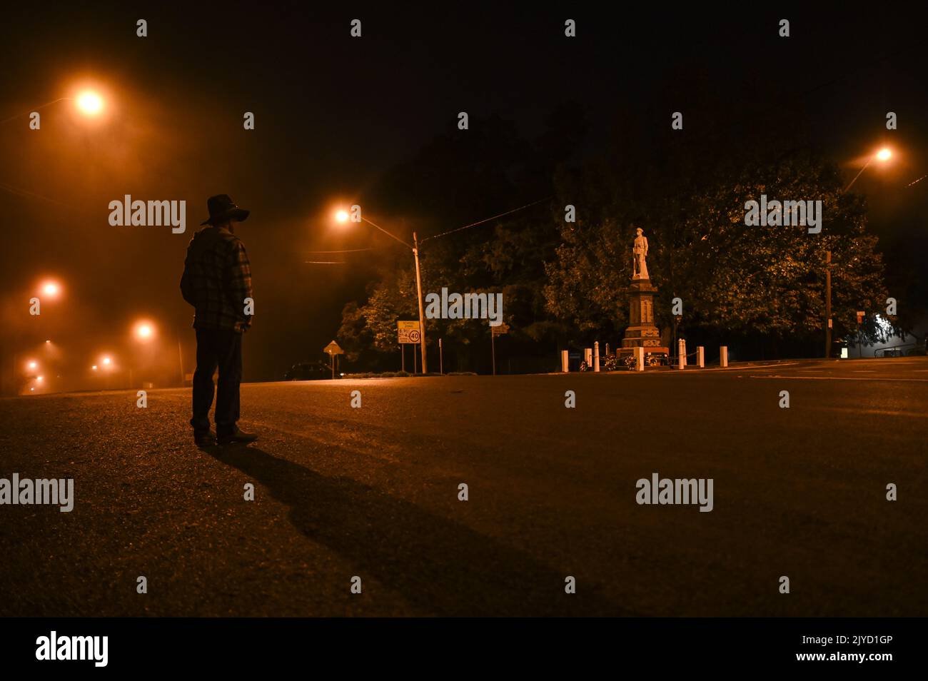 A resident pauses in front of the Braidwood cenotaph at dawn onAnzacDay