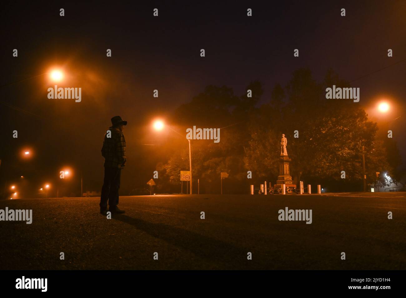 A resident pauses in front of the Braidwood cenotaph at dawn onAnzacDay