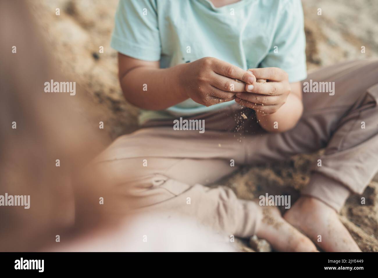 Little boy sitting in the sandbox and playing with sand on playground in summer. Summer vacation fun. Happy family, childhood. Summer outdoor fun Stock Photo