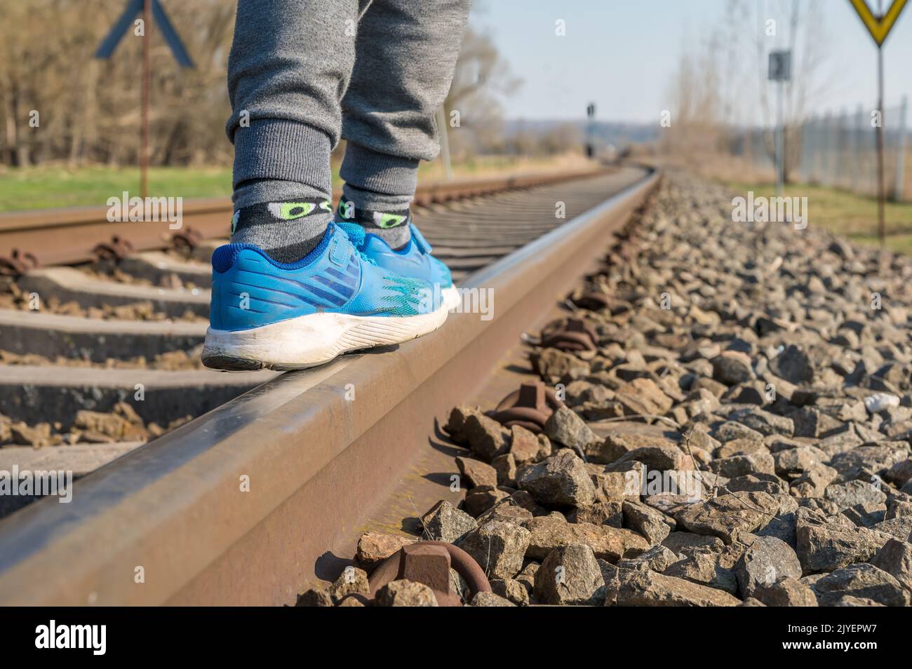 Child balances over tracks as a symbol for the violation of the parents' duty to supervise Stock Photo