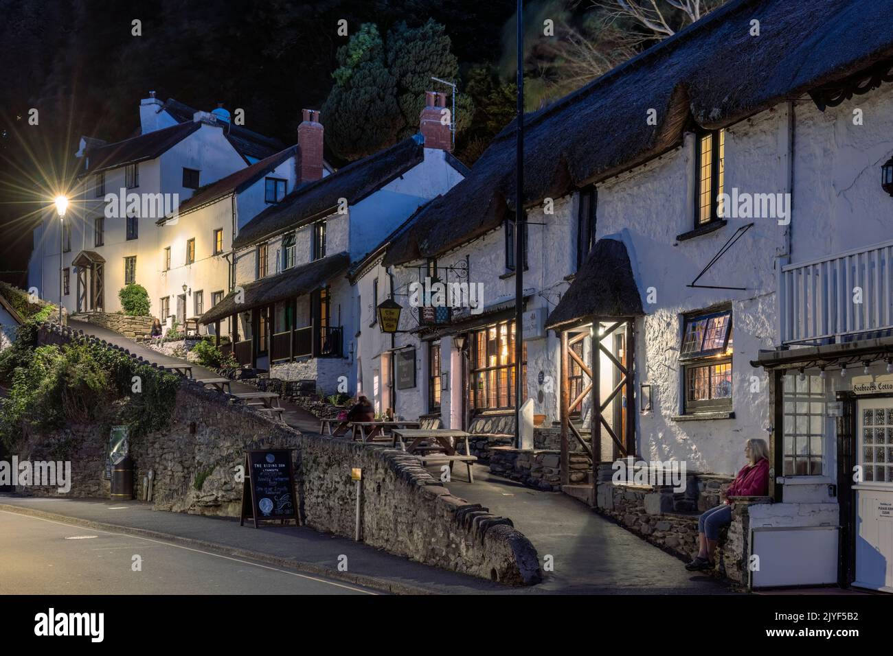 People enjoy a drink outside The Rising Sun Inn on the quayside at Lynmouth in North Devon. Stock Photo