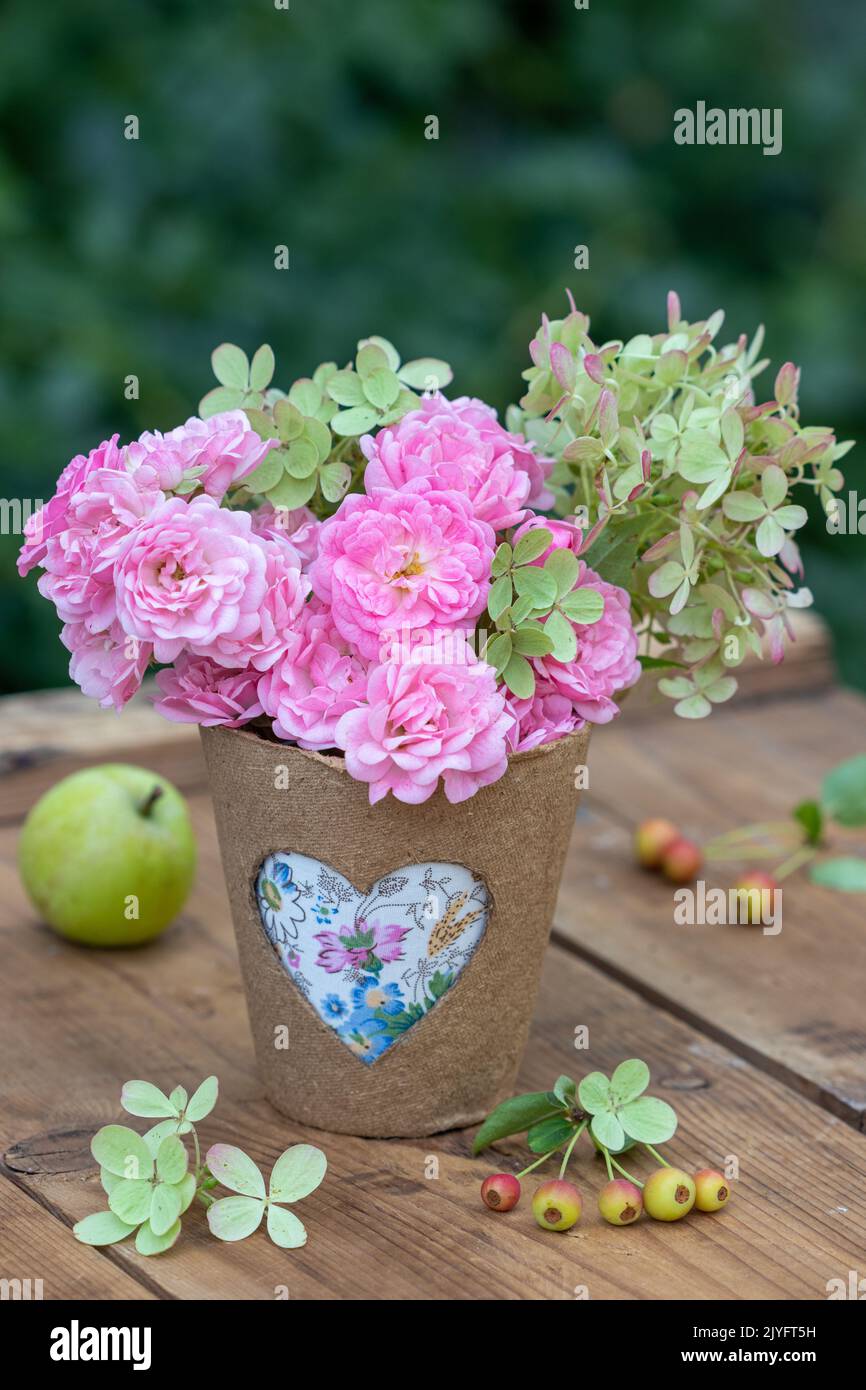 bouquet of pink roses and hydrangea flowers in biodegradable pot with heart ornament Stock Photo