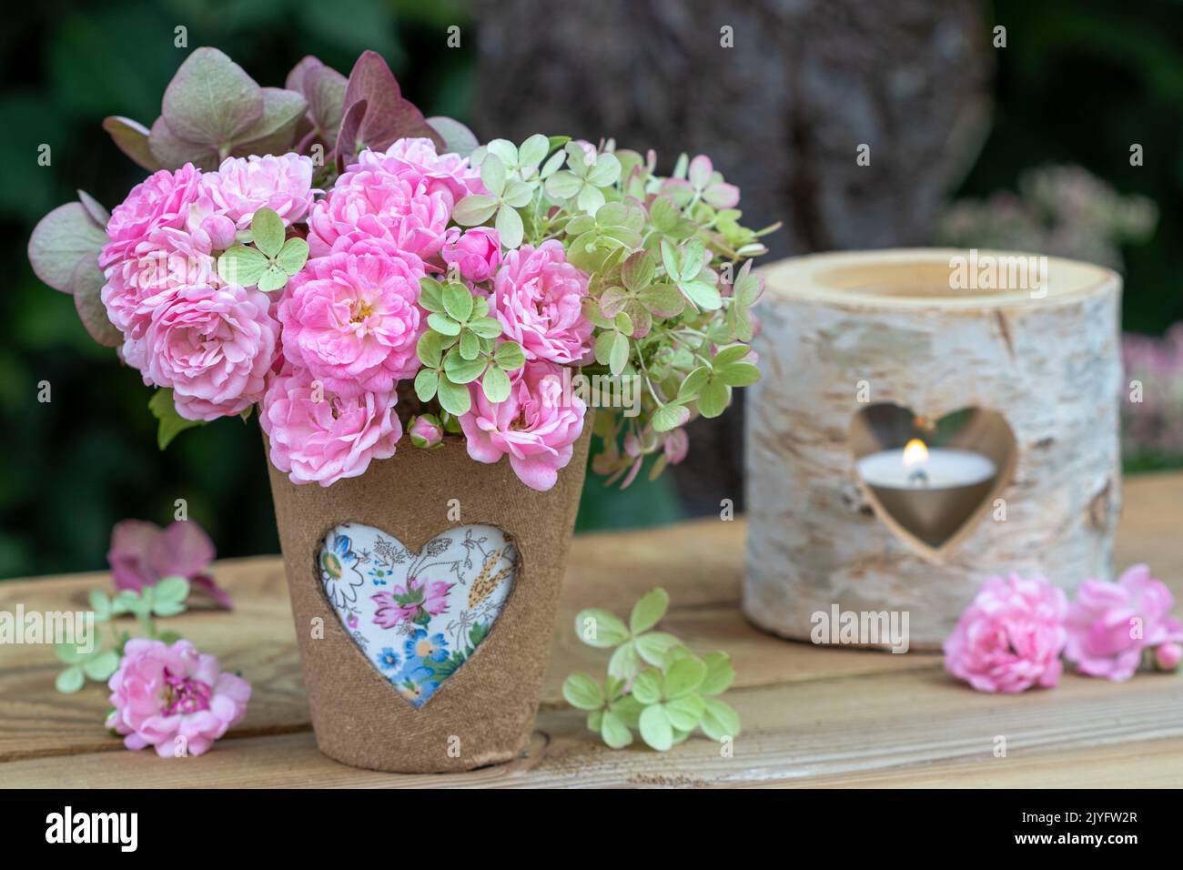 arrangement with bouquet of pink roses and hydrangea flowers and table lantern with heart ornament Stock Photo