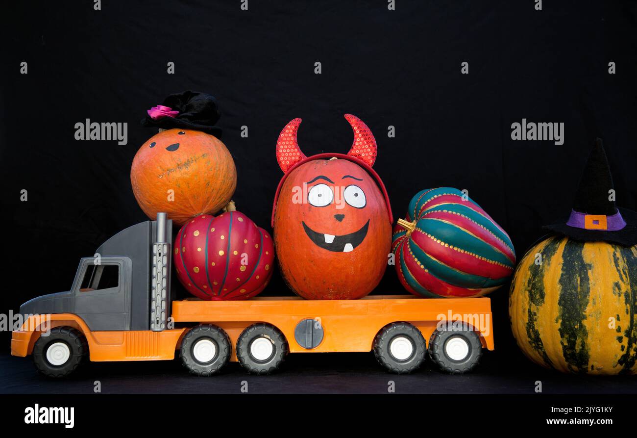 big kids toy truck loaded with lots of beautiful orange pumpkins. Preparation and delivery of decor for the terrible Halloween holiday. Festive street Stock Photo