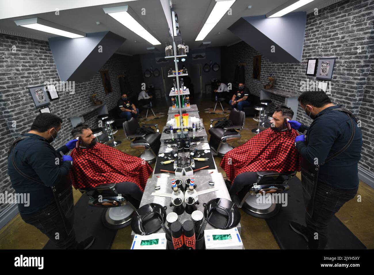 Barber Ethan Hemtyar (right) gives client Carlo Greco a hair cut at