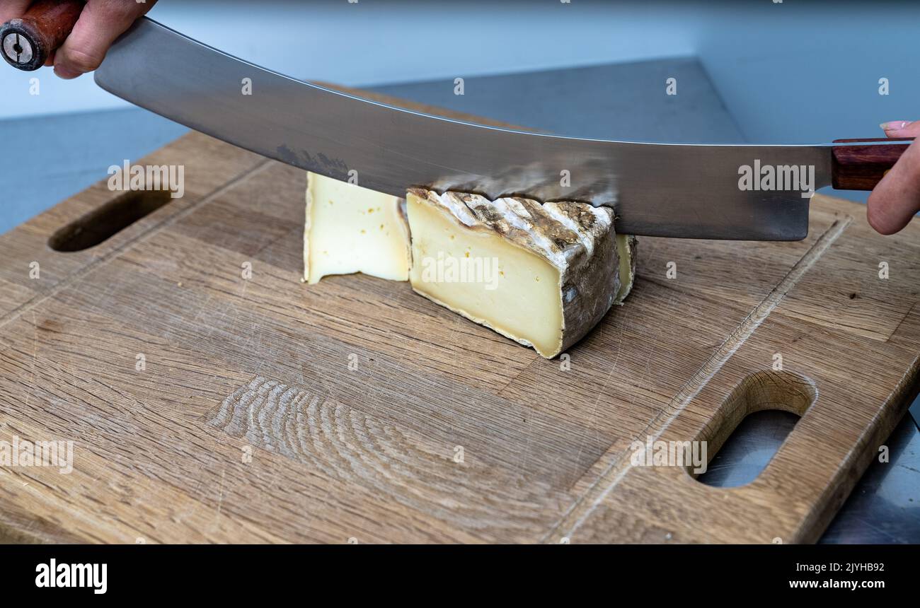 Cheese Knife cutting on a wooden board Stock Photo