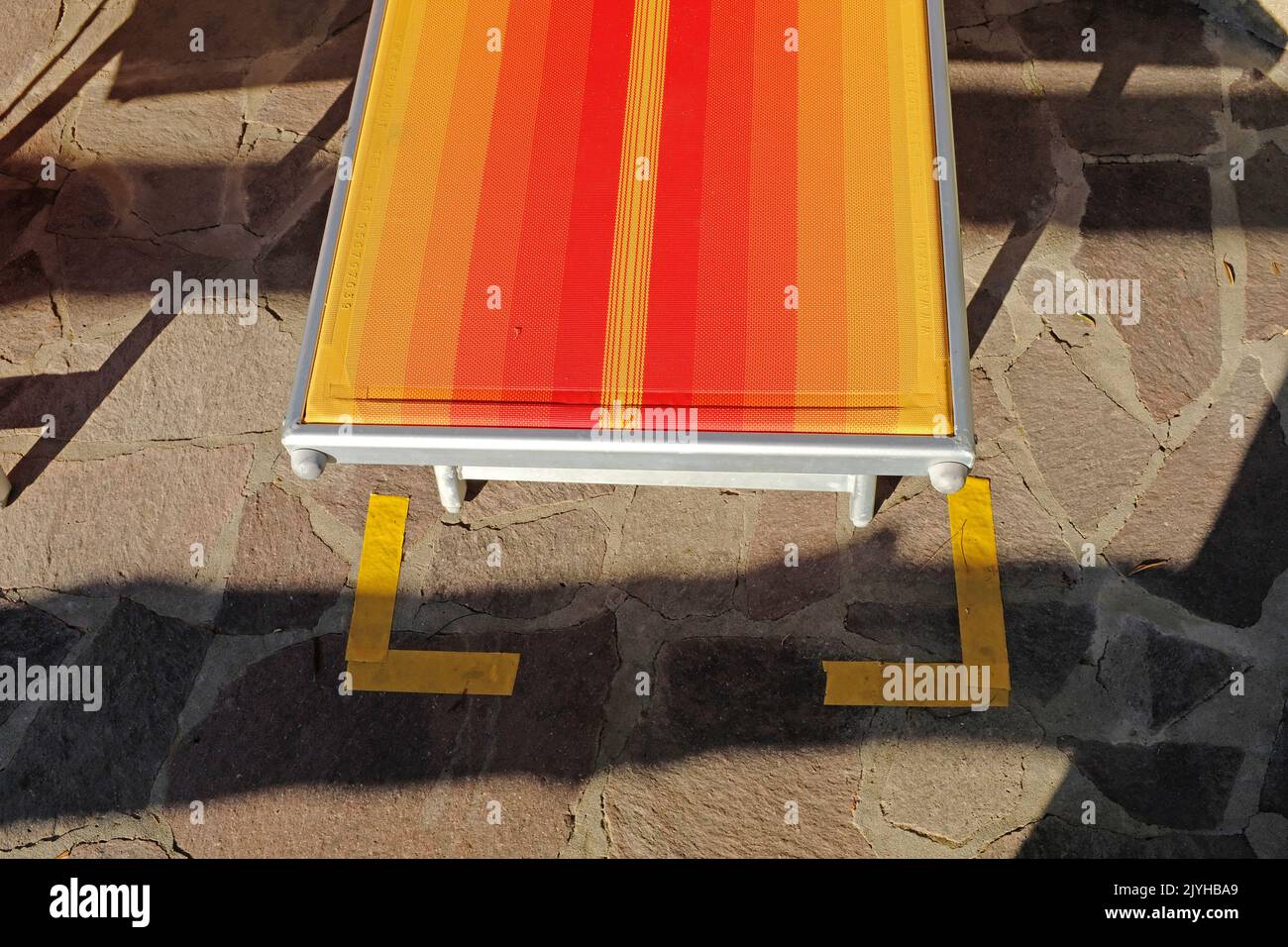 A sun lounger with Covid markings by a swimming pool. Stock Photo