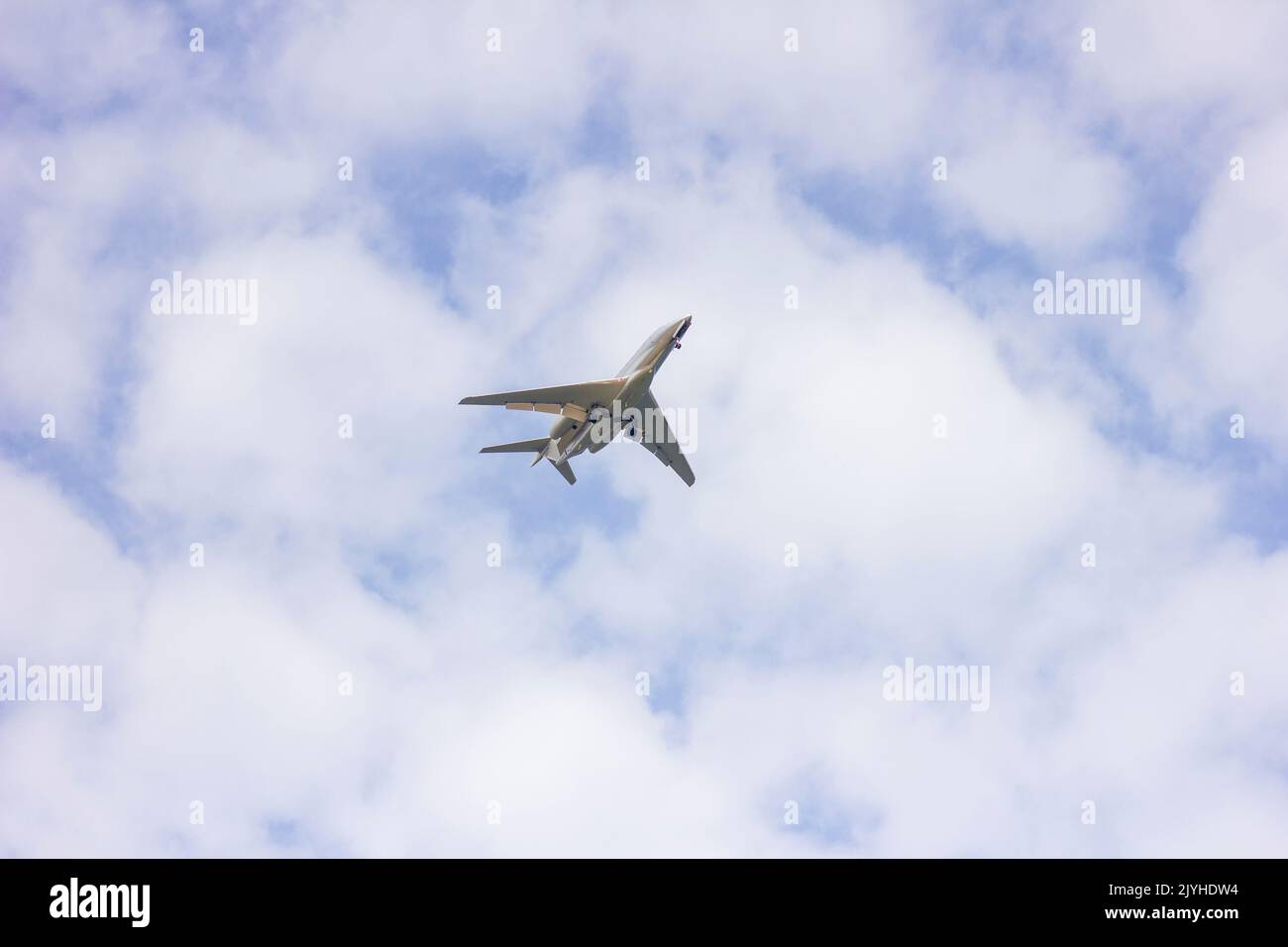 A portrait of a private plane flying low in a cloudy sky. The jet plane
