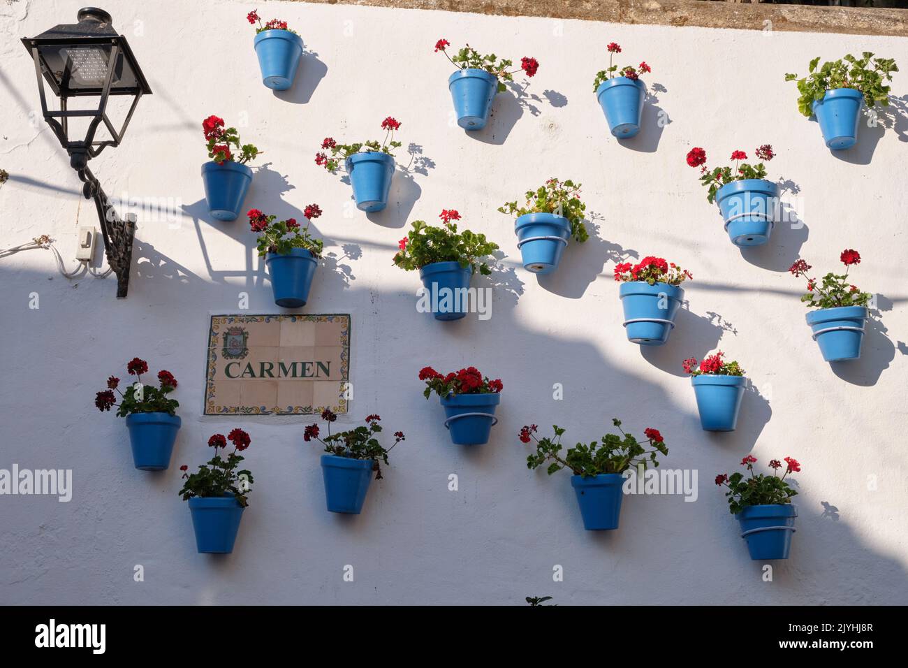 Blue pots with geraniums on white wall. Marbella, Spain. Stock Photo