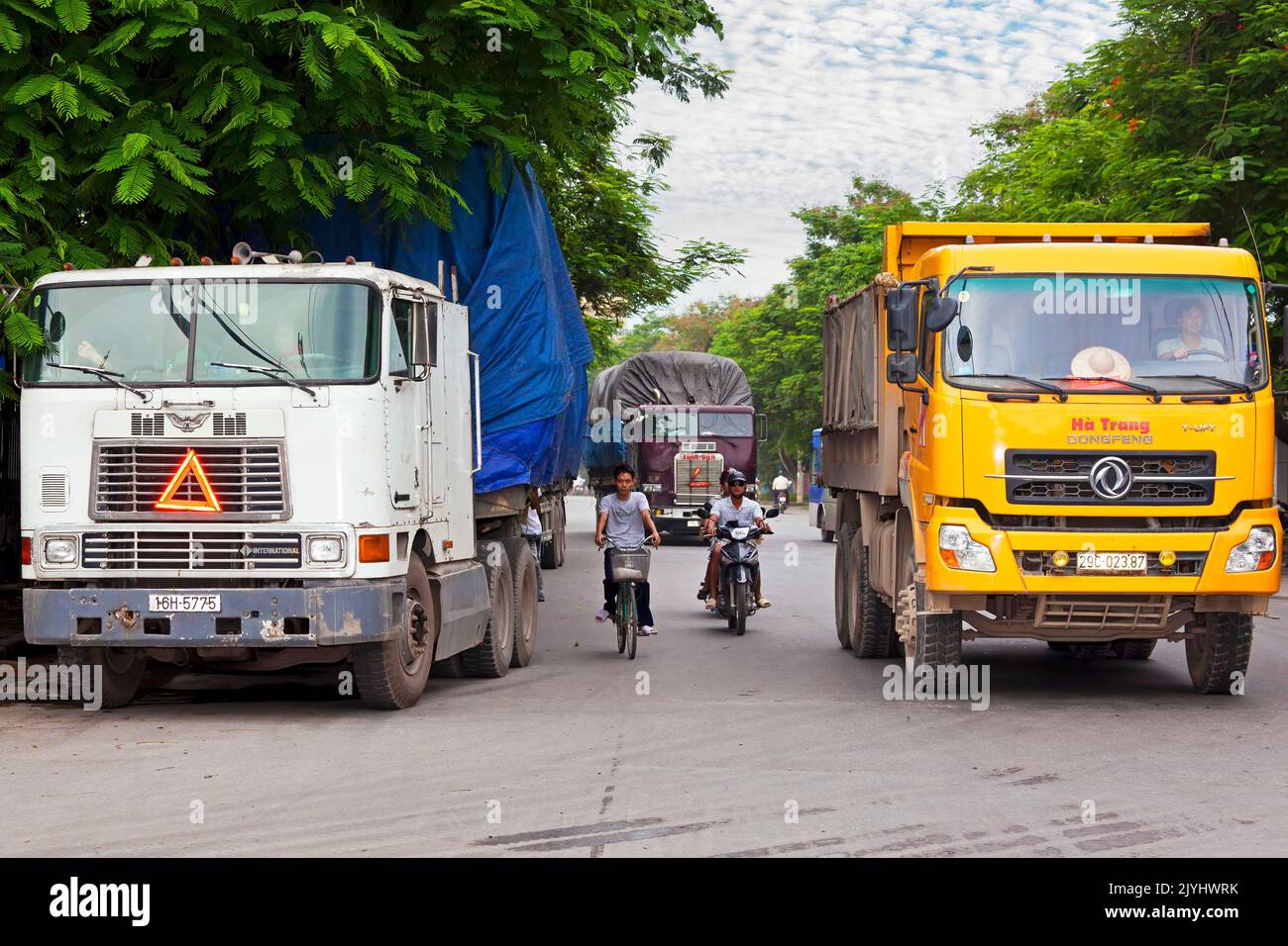 Container trucks and motorbikes in traffic, Hai Phong, Vietnam Stock Photo