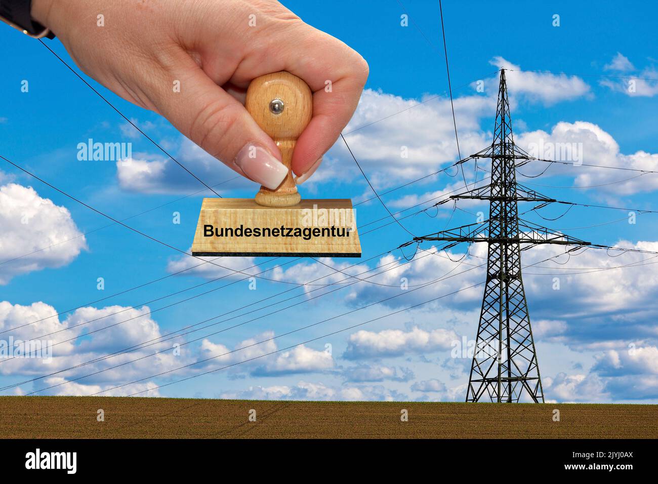 hand with stamp ketteriung Bundesnetzagentur, Federal Network Agency, FNA, power pole in the background, Germany Stock Photo
