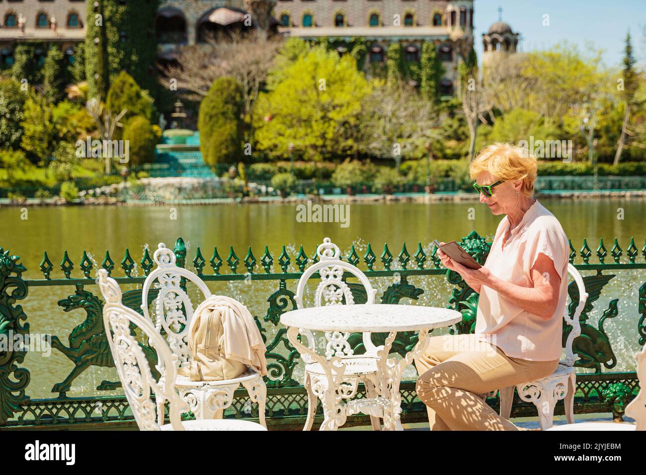 Mature attractive woman traveler sitting alone on the terrace of coffee ...
