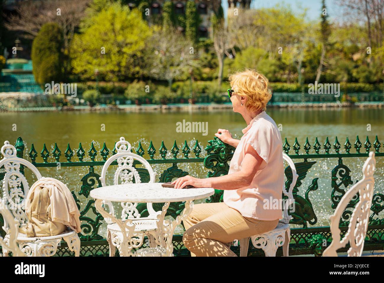 Mature attractive woman traveler sitting alone on the terrace of coffee ...