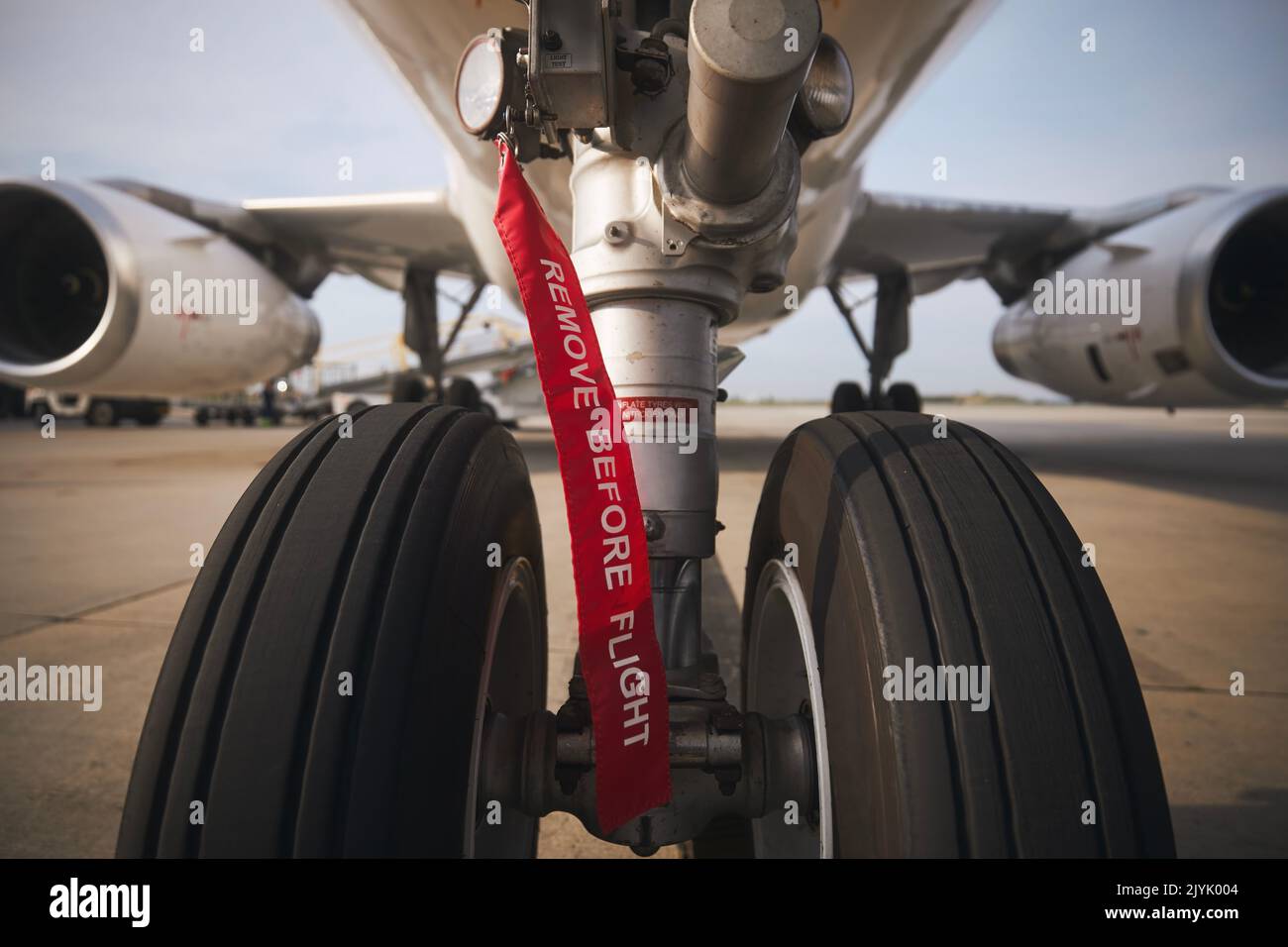 Aircraft nose wheel with red flag Remove Before Flight. Selective focus on airplane at airport. Stock Photo