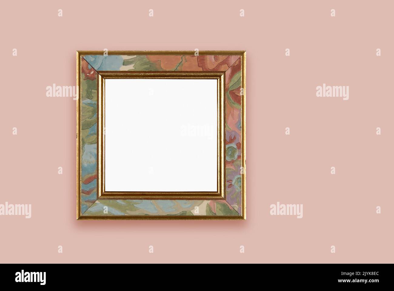 Gold edged frame with painted flower design. Hung on pink painted wall. With clipping path Stock Photo