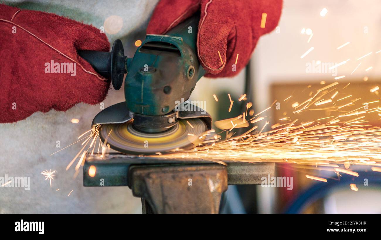 Craftsman grinding metal with disk grinder in Worker cleaning