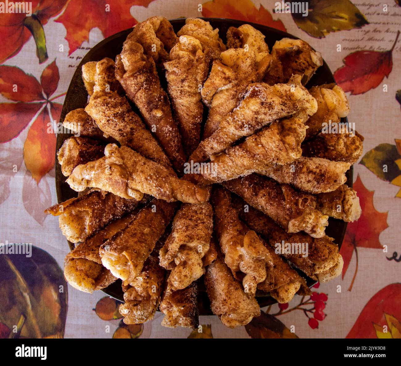Plato de cañas fritos rellenos de crema sobre un mantel de flores Stock Photo