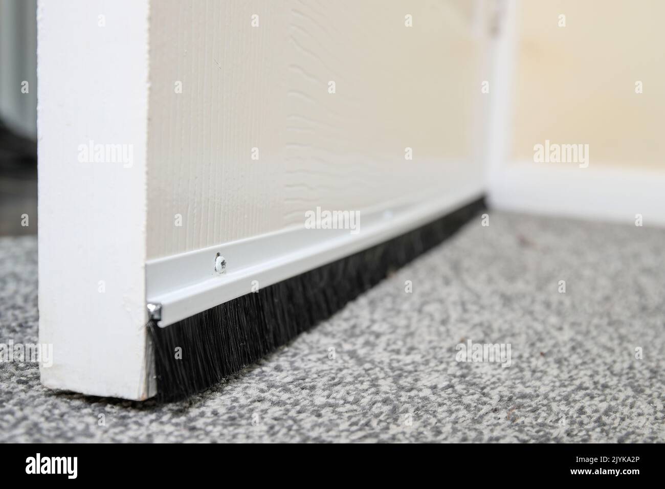 A Man fitting a draught excluder to a door in the UK to reduce heat