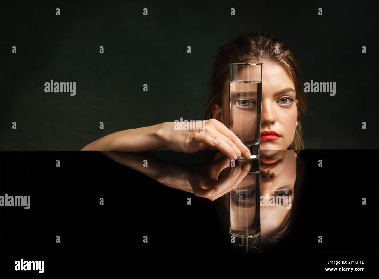 Contemporary art portrait of pretty girl looking through glass of water ...