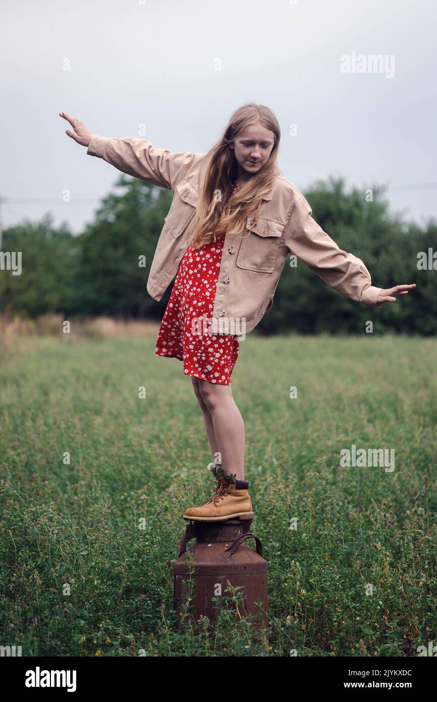 rural aesthetic. girl stands on an old milk can Stock Photo