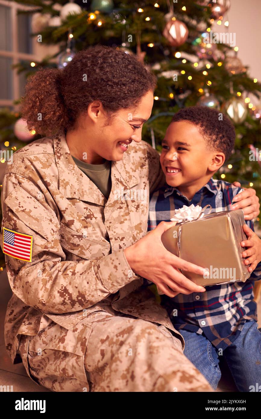 American Female Soldier In Uniform Home On Leave For Christmas Giving Son Present Stock Photo