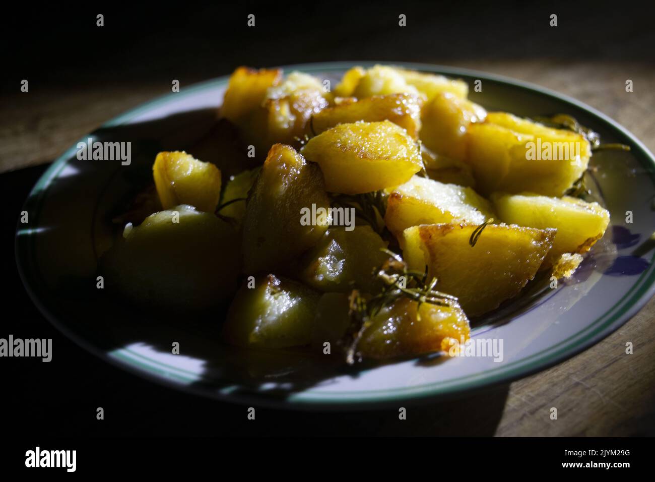 dish of baked potatoes with herbs and chiaroscuro light Stock Photo