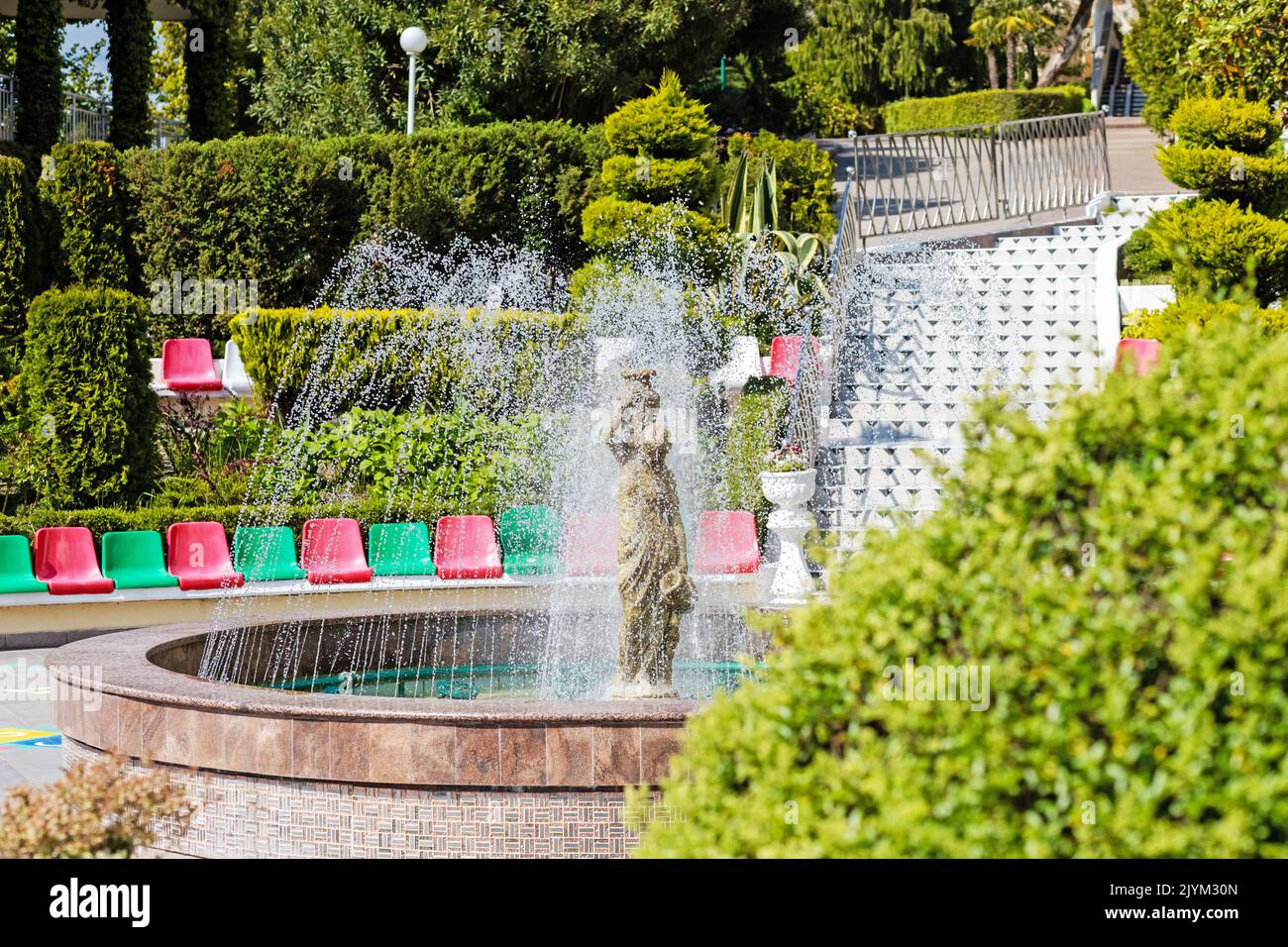 A fountain pours over a statue of a woman. Water splashes and stone