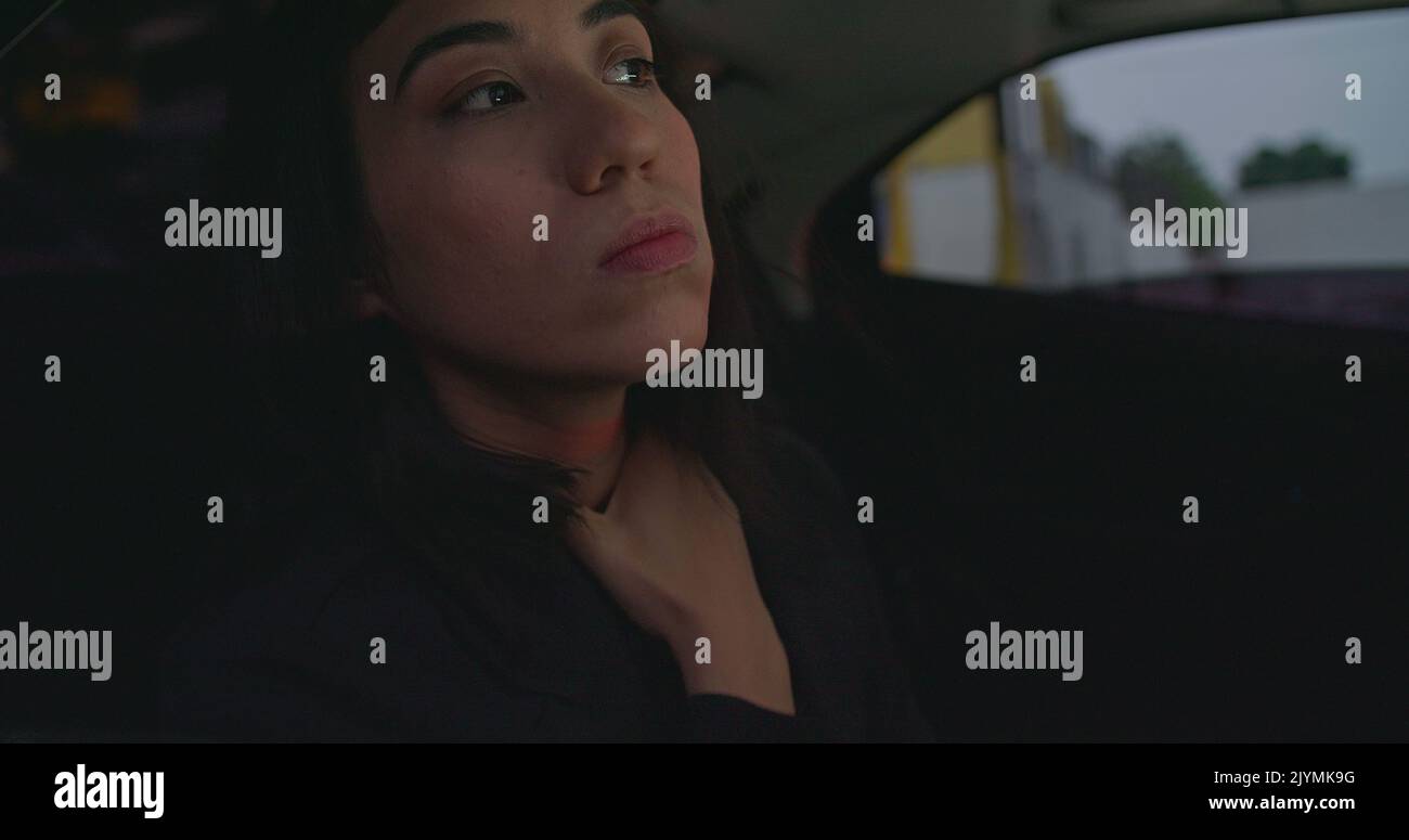 Anxious female passenger late for meeting in the backseat of a car