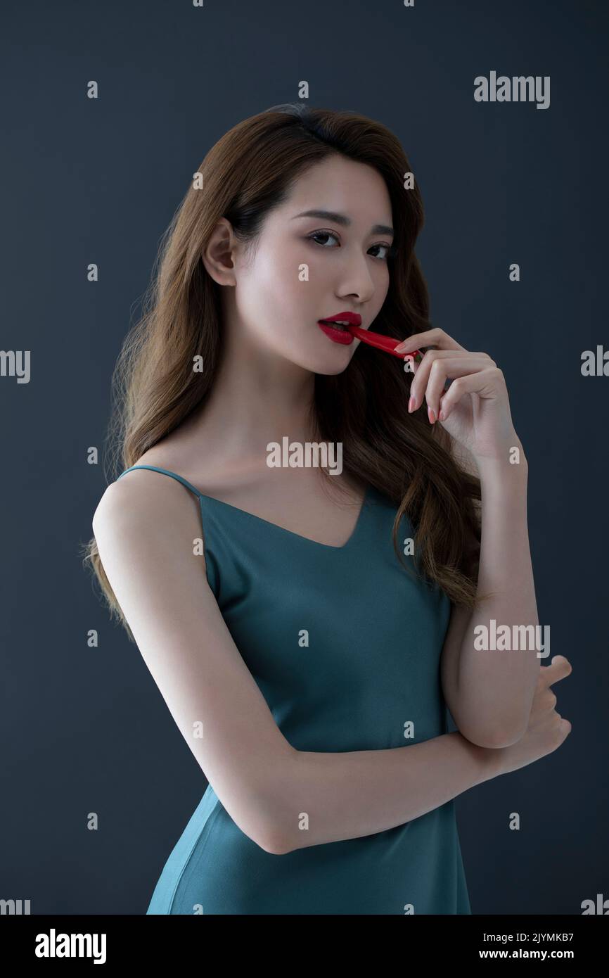 Beautiful young Chinese woman with red chili pepper Stock Photo - Alamy