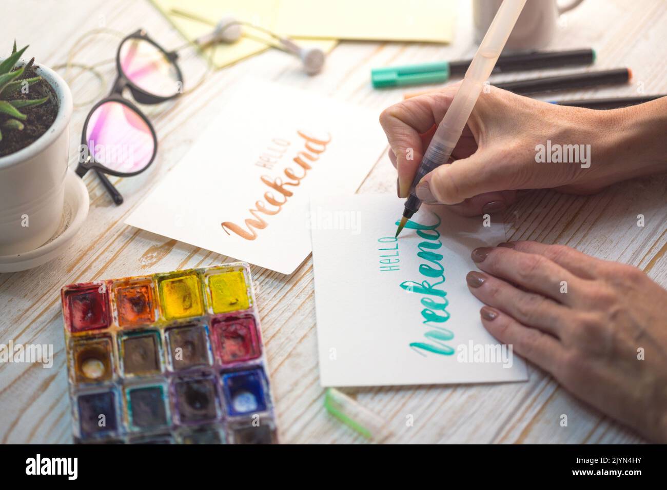 girl makes the inscription watercolor - hello weekend Stock Photo - Alamy