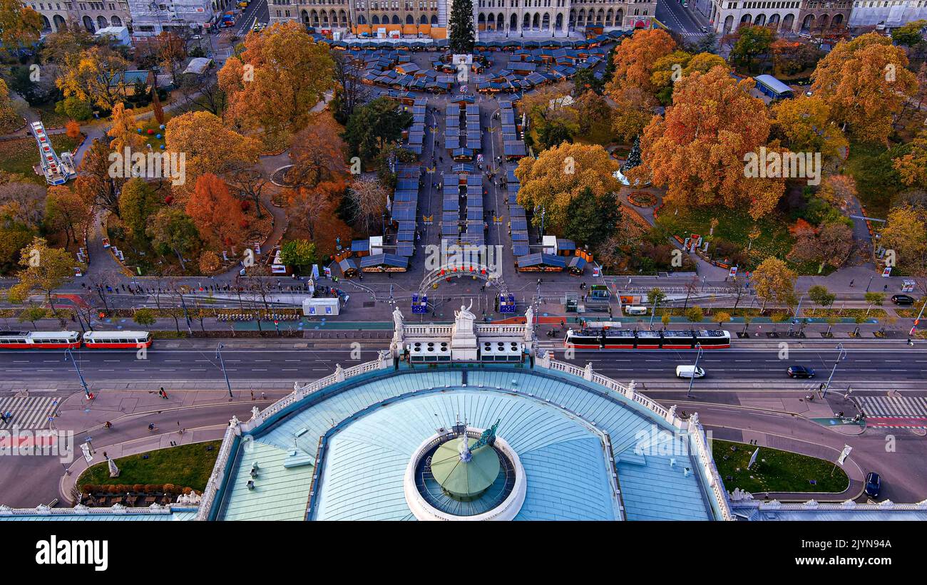 Looking down on worldwide famous Burgtheater flying over Rathaus Park along approaching Vienna City Hall ft cinematic aerial shot. Stock Photo