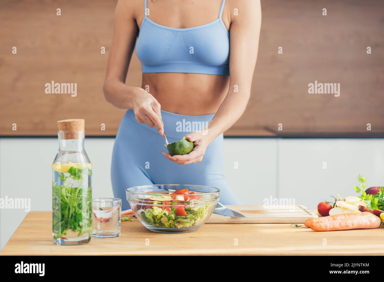 Close up photo, body part, hands of young fitness woman making salad with fresh vegetables and fresh detox eap in kitchen at home Stock Photo
