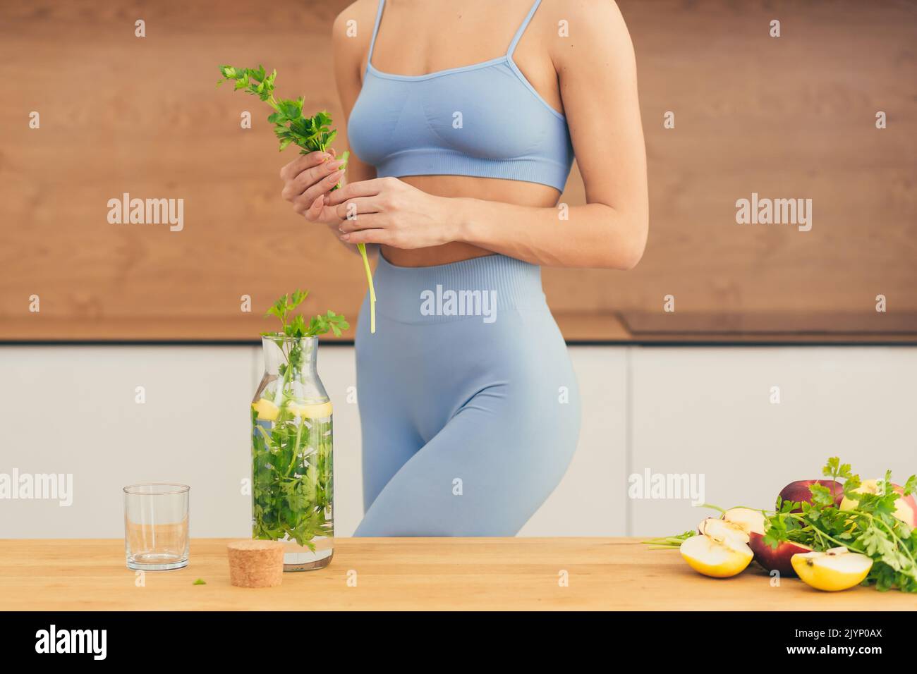 Close up photo, body part of young beautiful fitness woman preparing detox drink with fresh fruits, mint and lemon at home in the kitchen Stock Photo