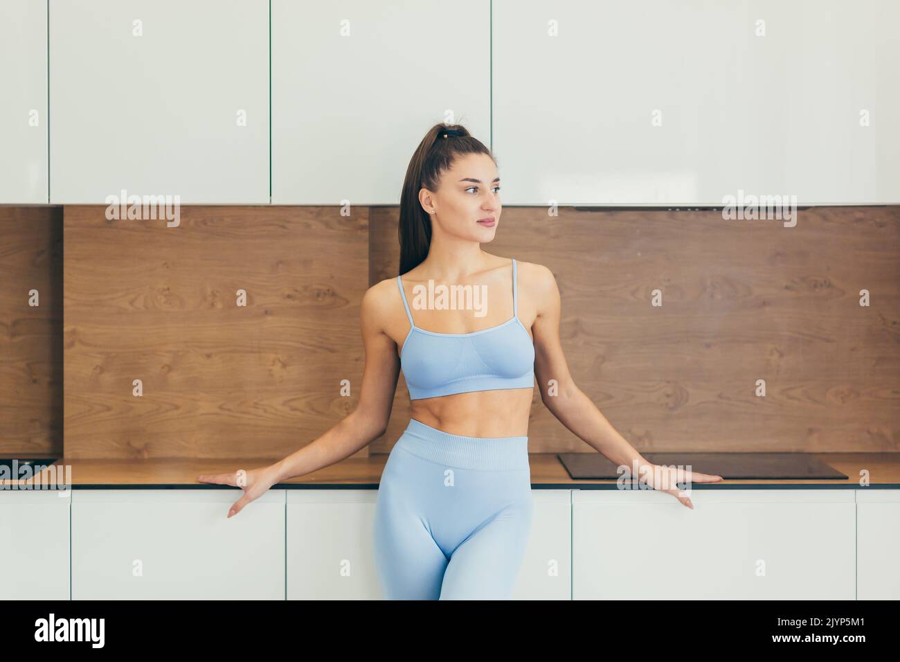 Close up photo Portrait of young beautiful sporty woman, fitness trainer at home, standing, looking aside Stock Photo