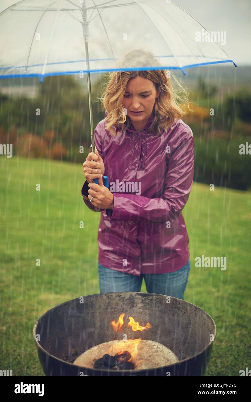 Keep burning flame. a woman having a barbecue outside in the rain while ...