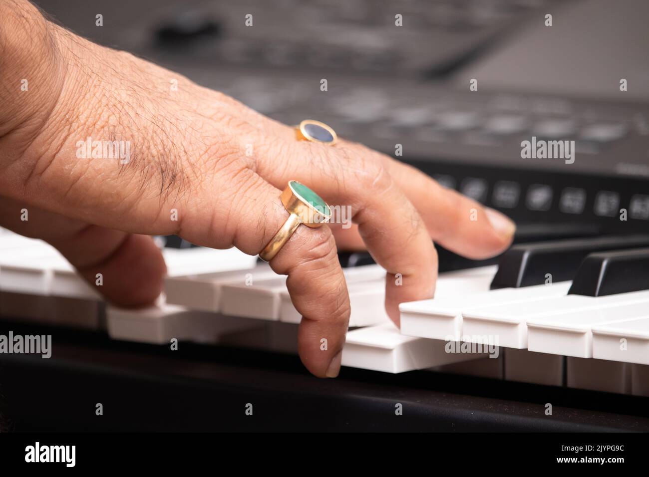 Hands Of Man Wearing Emerald Natural Panna And Blue Sapphire Neelam Gemstone Playing Notes On Piano Or Keyboard. Musical Training Or Coaching, Live Mu Stock Photo
