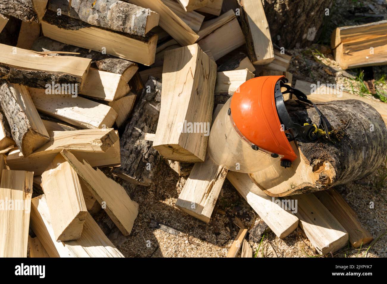 a pile of chopped firewood and a protective mask to protect the eyes Stock Photo