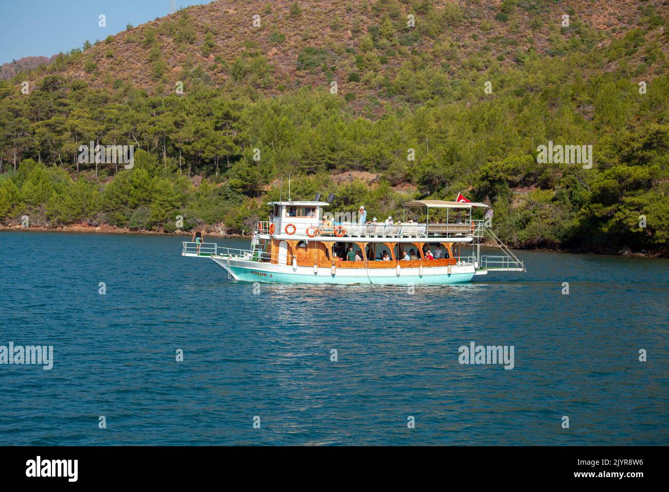 Pleasure yacht in the sea. Tourist ship with people on board with turkish flag sails on the waves. Fast moving excursion ship boat. Marmaris, Turkey - Stock Photo