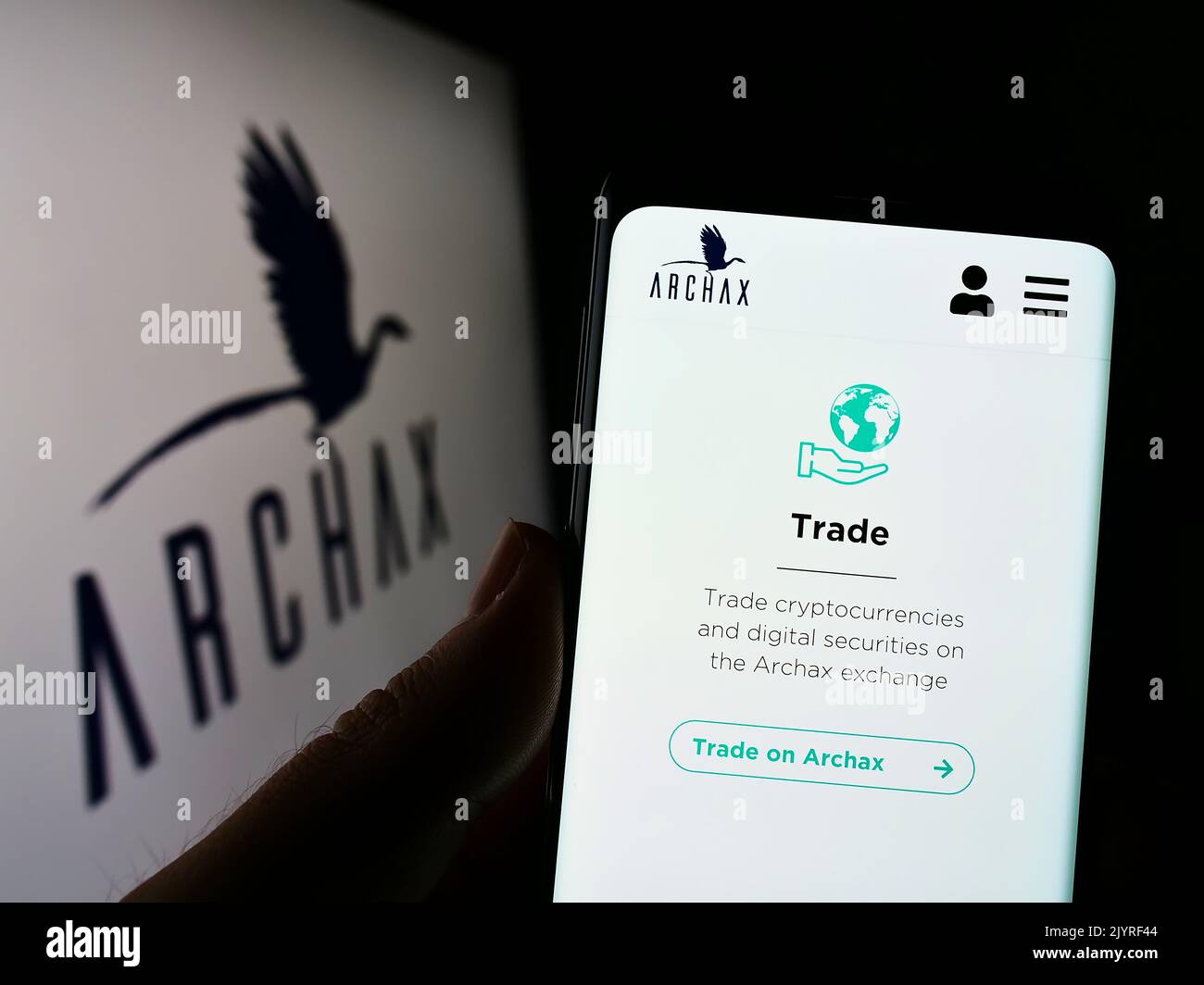 Person holding cellphone with website of British crypto company Archax Ltd. on screen in front of business  logo. Focus on center of phone display. Stock Photo