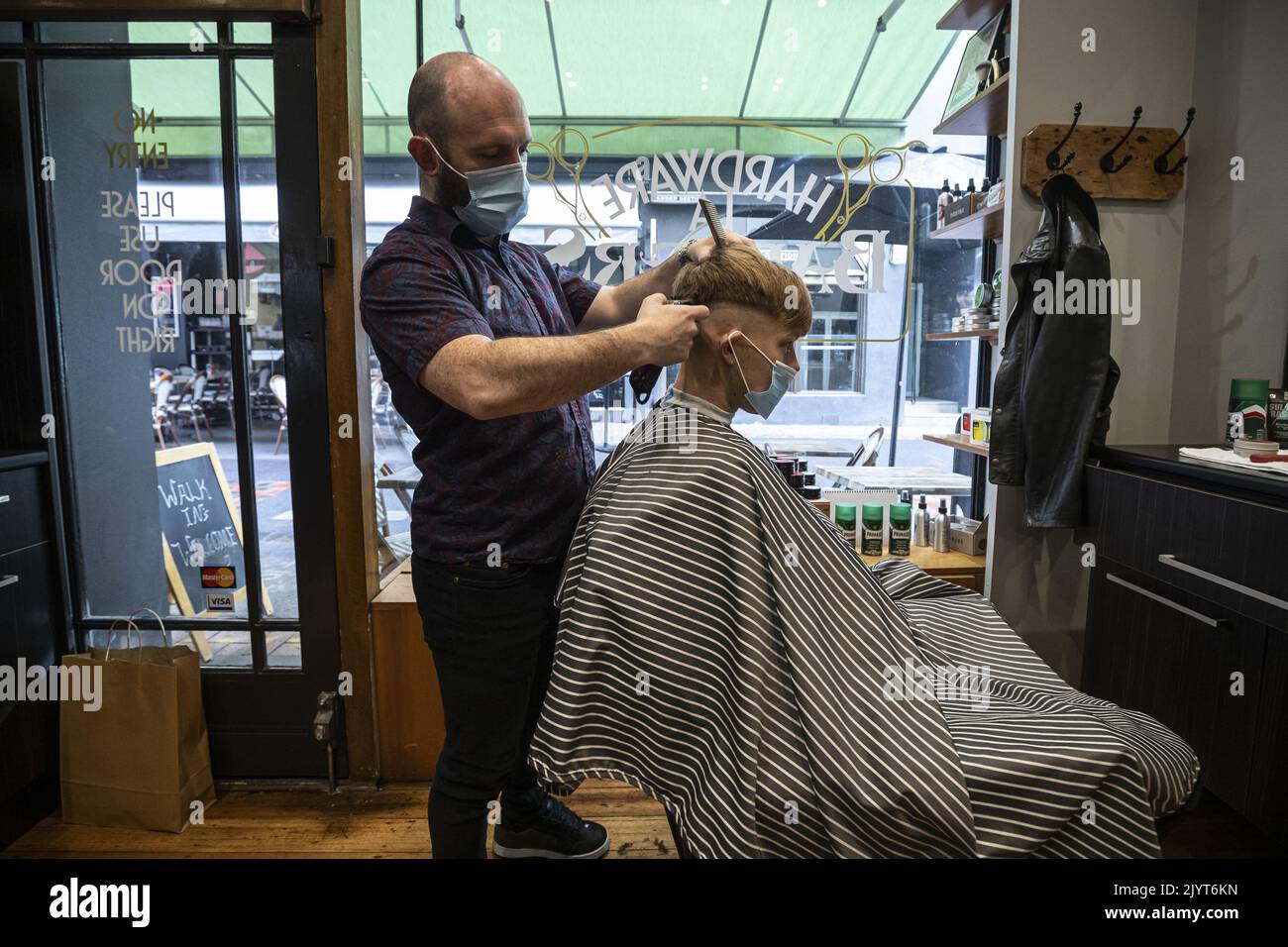 Customers receive haircuts in a Barber Shop along Hardware Lane in