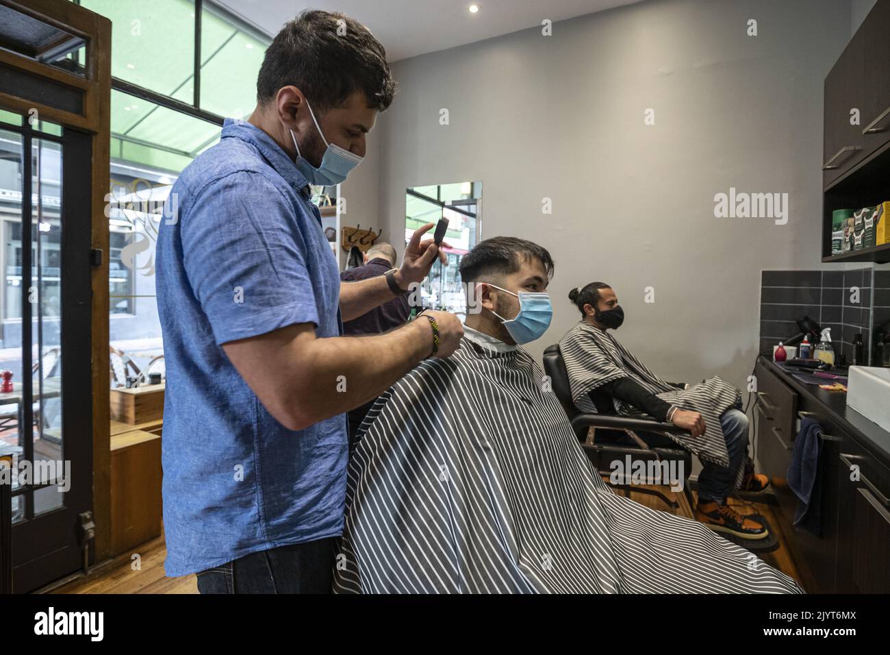 Customers receive haircuts in a Barber Shop along Hardware Lane in