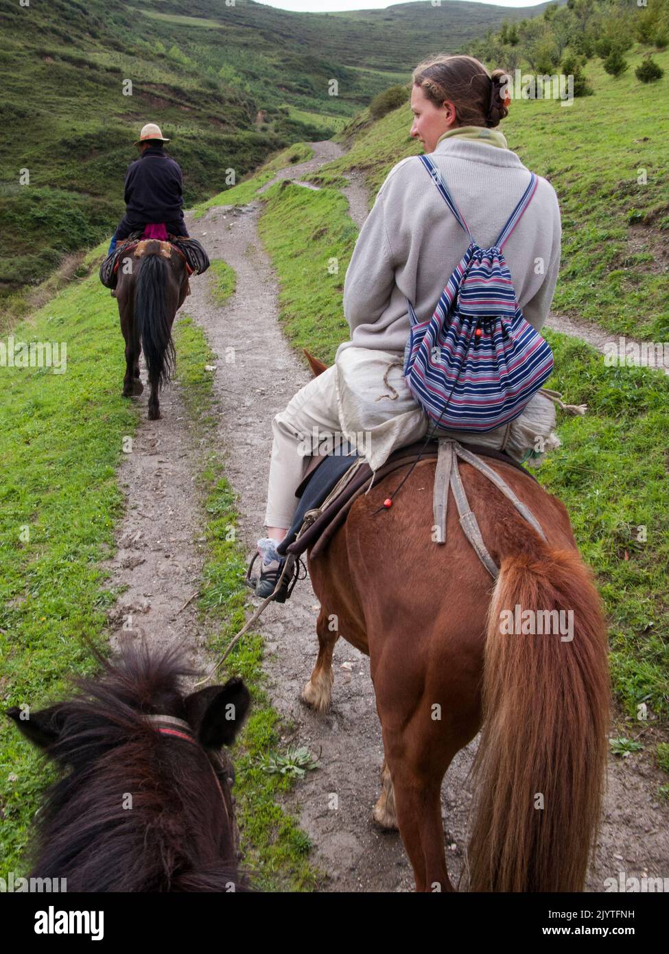 Horse trekking pony ride for Western and European holidaymaker, tourists and visitors given by Tibetan horseman / man / ethnic people of Tibet, resident or local to the walled ancient Chinese town of Songpan in northern Sichuan province, China. (126) Stock Photo