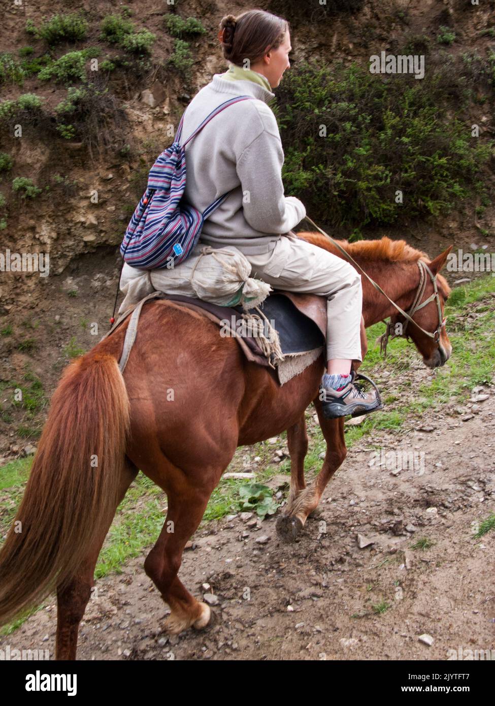 Woman rider on a horse trekking ride / trekking pony ride for western and European holidaymaker, tourists and visitors given by Tibetan  people of Tibet, resident or local to the walled ancient Chinese town of Songpan in northern Sichuan province, China. (126) Stock Photo