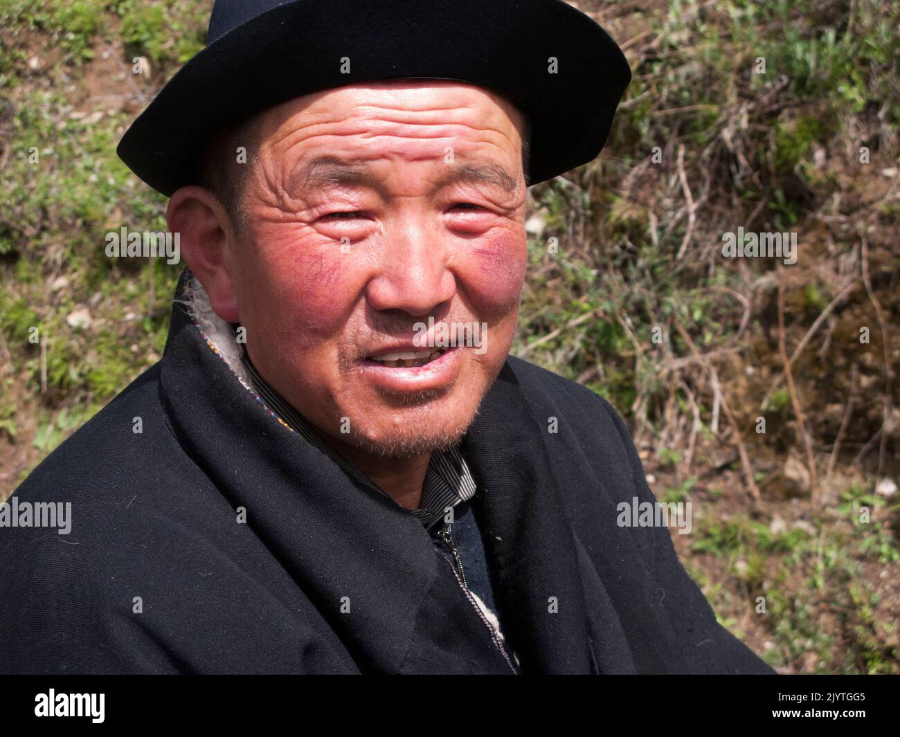 Face of a Tibetan horseman / man / ethnic person of Tibet, resident or local to the walled ancient Chinese town of Songpan in northern Sichuan province, China. Leader of a horse trekking pony ride for western European holiday makers, tourists and visitors, portrait but without his horse. (126) Stock Photo