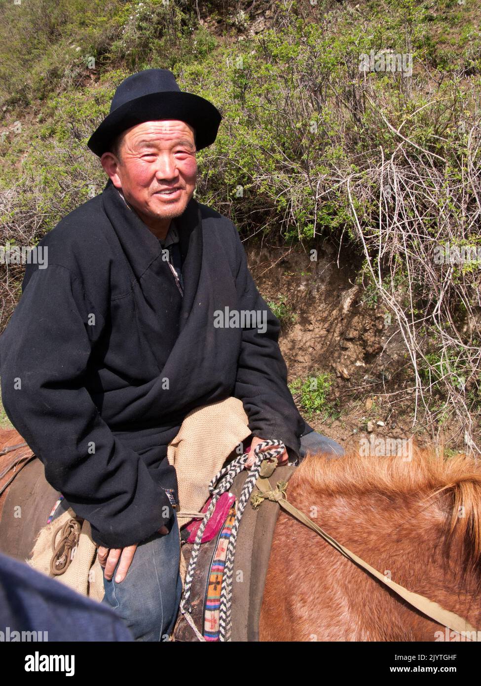 Horse trekking pony ride for Western and European holidaymaker, tourists and visitors given by Tibetan horseman / man / ethnic people of Tibet, resident or local to the walled ancient Chinese town of Songpan in northern Sichuan province, China. (126) Stock Photo