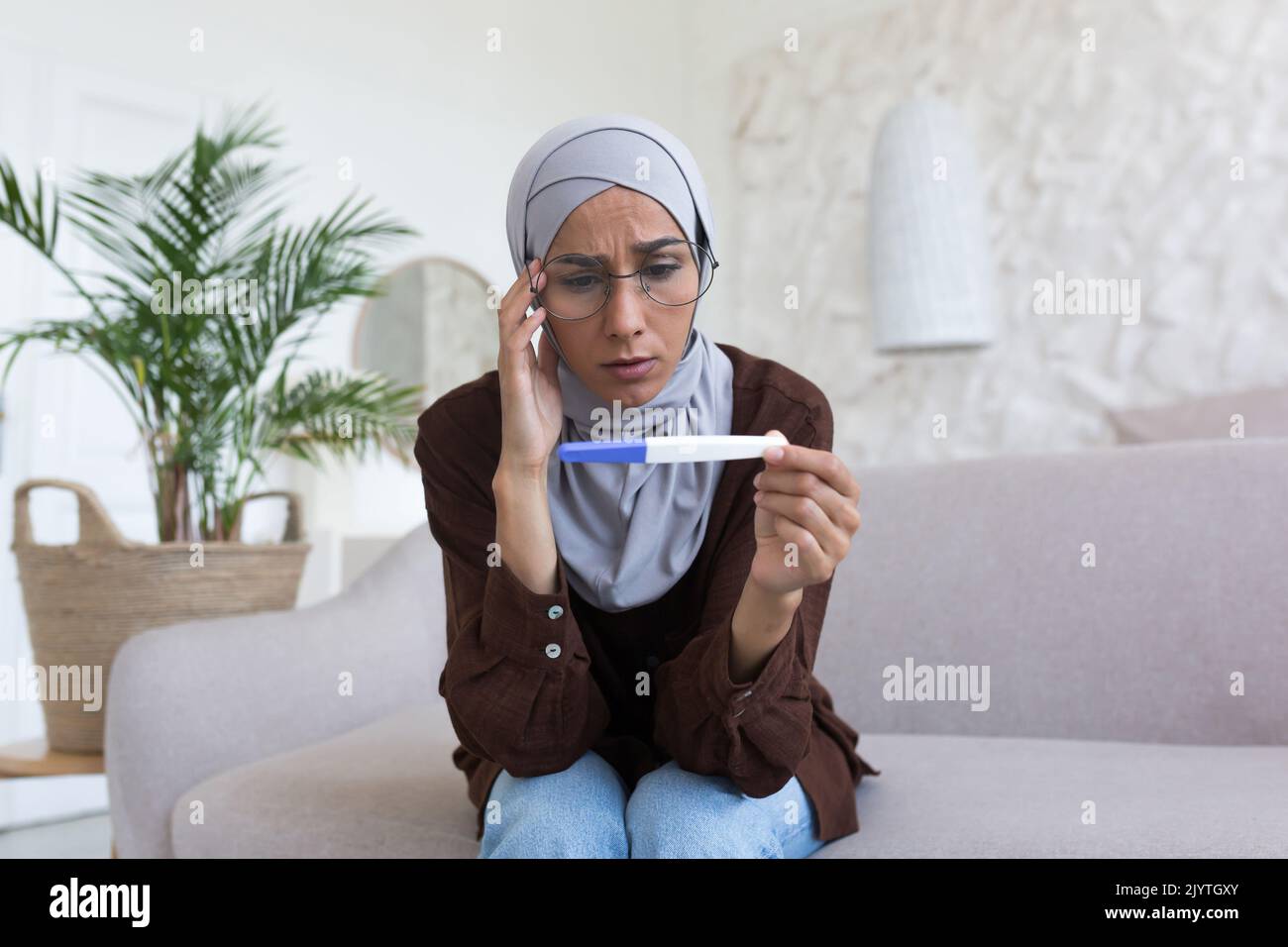 Upset Muslim woman in gray hijab and glasses, Arab holding pregnancy ...