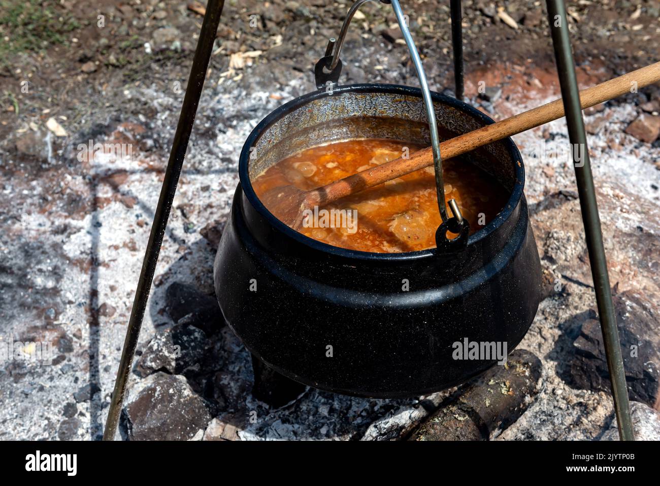 Cooking goulash in a cauldron on an open fire in the nature. Stock Photo